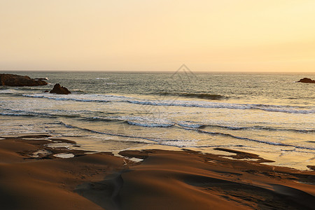 海洋日落是明亮的金色海景 温柔的波浪滚滚向岸边图片