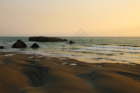 太平洋海岸带岩石的桑迪海滩日落海岸旅行海洋灌木悬崖沙丘编队环境支撑图片
