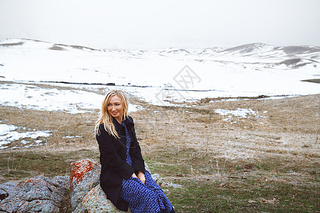 冬天风景中微笑的女人双臂孤独腰部岩石田园冒险风光金发草原女性图片