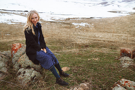 冬天风景中微笑的女人女性石头孤独农村场地水平草原双臂金发岩石图片