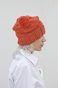 穿着温暖橙色豆子的年轻美女白色羊毛针织手工女性帽子美丽女士金发橙子图片