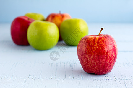 红苹果和绿苹果放在木制蓝色桌子上图片