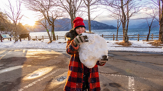 年轻女孩有巨大的雪球日光混血微笑手套童年图片