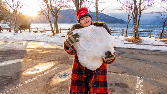 年轻女孩有巨大的雪球手套日光混血微笑童年高清图片
