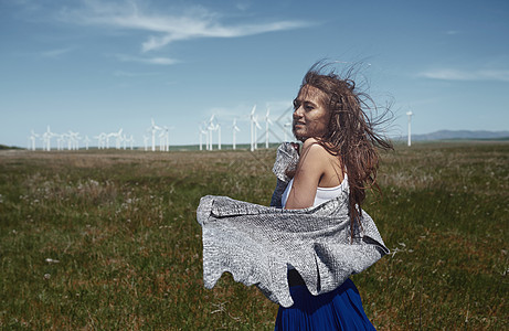在风力涡轮机旁边 长发缠头发的女人燃料自然界可持续力量女士能源开襟衫环境保护水平轮机图片