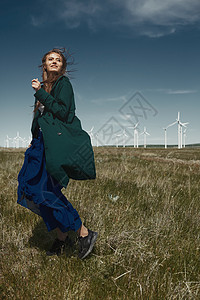 在风力涡轮机旁边 长发缠头发的女人女士燃料自然界外套可持续能源发电力量生活方式轮机图片