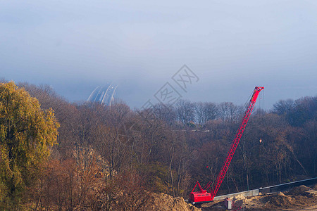 建筑工序 建造装有红色刺青的汽车起重机;秋雾和河桥 地铁列车背景模糊;起重机周围森林图片