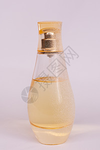 暖黄色玻璃香水瓶 白色紫色背景上有人造雪 特写视图金子香气卫生反射香味香水礼物气味化妆品女性背景图片