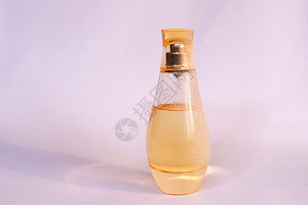 暖黄色玻璃香水瓶 白色紫色背景上有人造雪 特写视图金子香水化妆品气味香味魅力液体优雅男人卫生图片