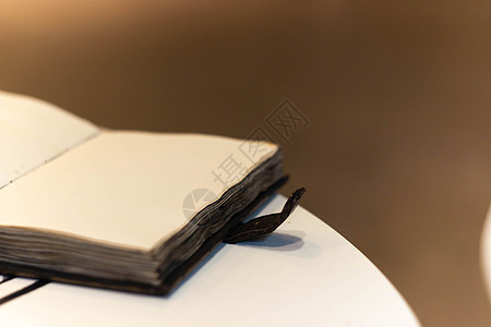 手工制作的魔法笔记本 封面上有塔符号 皮革封面和里面的手工床单 笔记本的第一页有 12 个星座 非常模糊的背景 软焦点放在笔记本图片