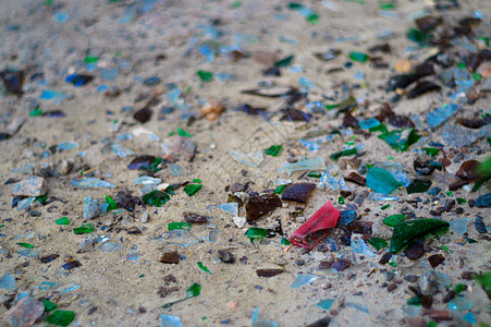白色沙滩上的碎玻璃瓶 瓶子是绿色和蓝色 沙滩上的垃圾 生态问题事故环境酒精塑料地面粉碎杯子危险饮料回收图片