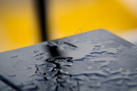 黄色背景的雨后黑木桌 许多水滴在桌子上 血缘是黑色的图片