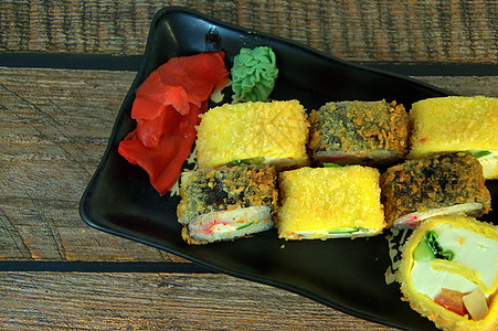 木制桌上黑陶瓷板上的姜汁和黄蜂 烤寿司 近距离拍摄午餐用具菜单小吃美食食物黄瓜餐厅盘子寿司图片
