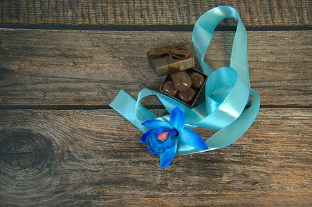 一盒巧克力 蓝色丝带 蓝色兰花花蕾和木桌上的装饰球庆典风格展示礼物生日包装念日木头糖果桌子图片