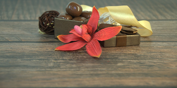 一盒巧克力 装饰性球 红兰花和米色丝带的芽 在木制桌子上糖果表格风格纸板作品庆典装饰情调生日异国图片