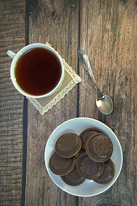 木桌上放着早餐 一杯茶和饼干 瓷杯和勺子上放着巧克力糖霜营养茶匙食物盘子桌子红茶横幅液体海报糖果图片