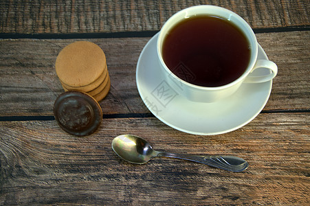 一杯黑茶放在瓷锅上 一勺勺子和一堆带巧克力的海绵饼干 躺在木制桌子上营养咖啡店液体海报甜点早餐杯子食物草本植物厨具图片