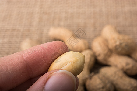 手持花生和亚麻布背景的花生小吃食物饮食养分种子坚果营养图片
