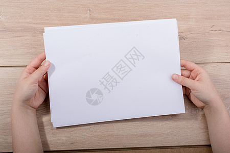 手拿纸在木制背景上白色文档笔记办公室床单木头商业图片