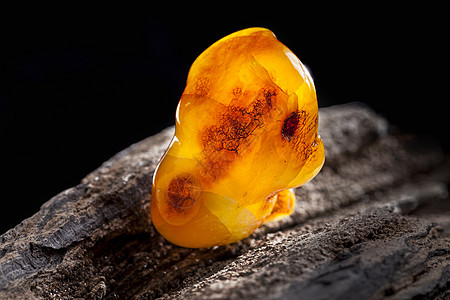 天然琥珀 黄色不透明的天然琥珀 在大片黑石头木头上宏观蜂蜜珠子材料珠宝分层化石宝石矿物裂缝图片