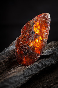 天然琥珀 一块黄色和红色半透明的天然琥珀 放在一块石头上化石琥珀色宏观裂缝太阳石蜂蜜宝石晴天抛光地质学图片