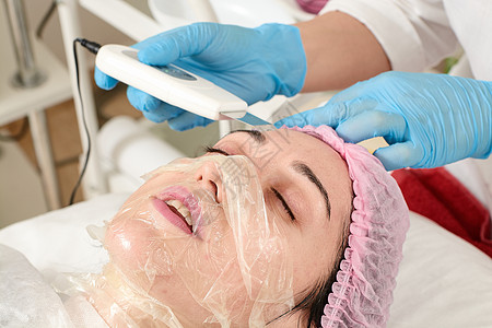 在美容院的年轻女子 做剥皮和面部清洗程序诊所超声波电泳美容护理化妆品电疗按摩器沙龙美容师图片