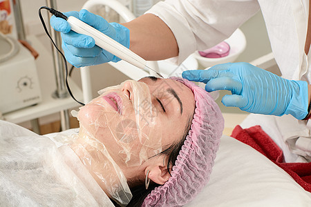 在美容院的年轻女子 做剥皮和面部清洗程序按摩按摩器皮肤女士除垢电疗护理仪器刺激治疗图片