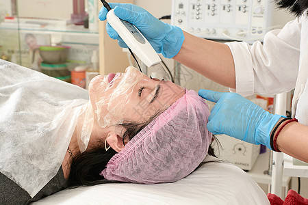 在美容院的年轻女子 做超声波剥皮 和面部清洗程序药品治疗电疗刺激机器按摩器空化除垢医生化妆品图片