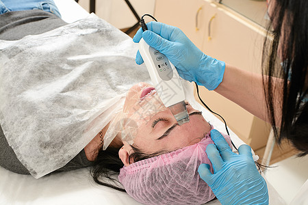 在美容院的年轻女子 做超声波剥皮 和面部清洗程序按摩机器刺激电疗美容师治疗护理温泉仪器诊所图片