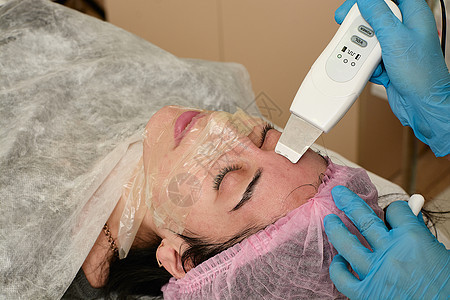 在美容院的年轻女子 做超声波剥皮 和面部清洗程序皮肤福利按摩器刺激机器美容电疗仪器硬件沙龙图片