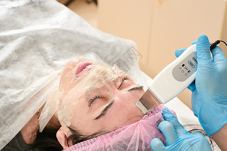 在美容院的年轻女子 做超声波剥皮 和面部清洗程序机器收音机诊所护理治疗温泉沙龙化妆品福利刺激图片