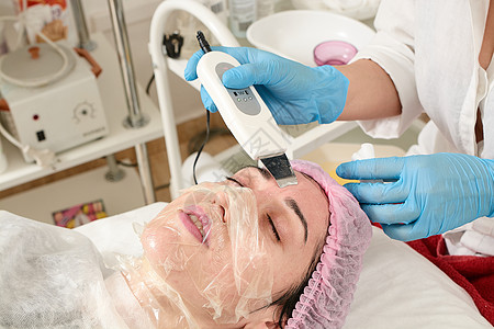 在美容院的年轻女子 做超声波剥皮 和面部清洗程序收音机化妆品药品刺激频率美容电泳治疗医生除垢图片
