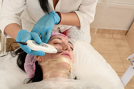 在美容院的年轻女子 做超声波剥皮 和面部清洗程序刺激美容温泉频率女士除垢硬件按摩器福利医生图片