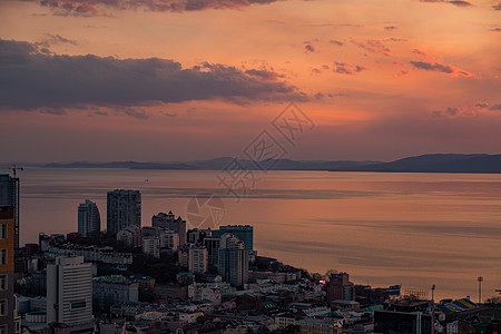 海参沃斯托克市的全景 与日落相对照港口天际中心船舶环境日落蓝色喇叭建筑学橙子背景