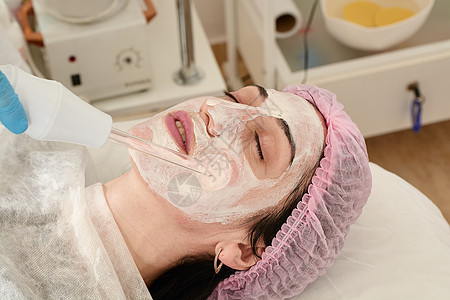 在美容院的年轻女子 确实恢复了活力 将程序Darsonval在脸上按摩器医生药品身体皮肤温泉美容师化妆品治疗皱纹图片