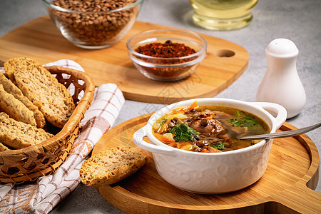 在灰色桌子和原料上的木板上 用白碗中的鸡肉汤和红菜汤烹饪香料勺子菜单美食蔬菜厨房面包盘子食物图片