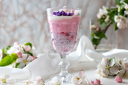 配有红椰子和苹果花的Chia布丁早餐食物种子紫色浆果杯子桌子叶子丝绸奶制品图片