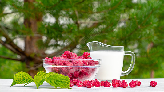 玻璃碗中的新鲜覆盆子和绿色背景下白色木桌上的天然酸奶 健康有机营养的概念水果叶子甜点浆果美食奶制品小吃照片牛奶桌子图片