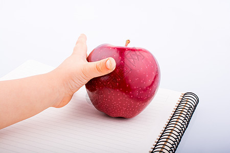 手拿着笔记本上的红苹果教科书床单水果笔记记事本字帖商业教育饮食日记图片