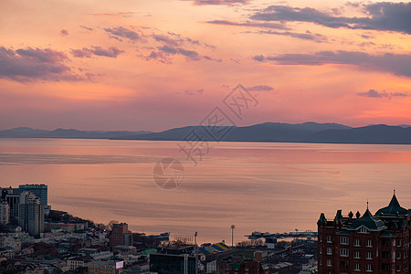 海参沃斯托克市的全景 与日落相对照建筑船舶橙子喇叭港口中心地区房子蓝色天际图片