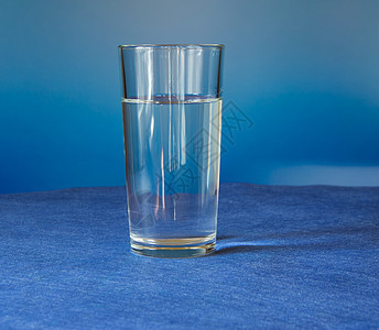 蓝色背景的桌子上是玻璃杯水背景图片