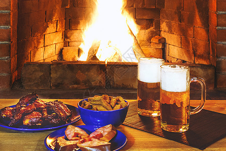 两杯啤酒 在壁炉附近的木制桌子上加点心美味饮料酒吧生活木头炙烤别墅熏制液体饼干图片