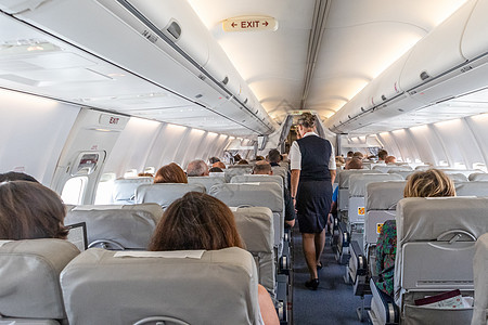 商业飞机内部 空姐在飞行期间坐在座位上服务乘客 b 客机内天空椅子航程走道经济航班娱乐走廊屏幕游客图片