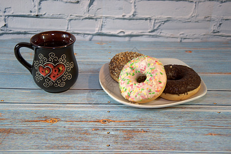一个装有茶的陶瓷杯和一个白色的瓷盘 上面有糖霜甜甜圈 特写面包蛋糕烹饪制品甜点餐具陶器团体桌子盘子图片
