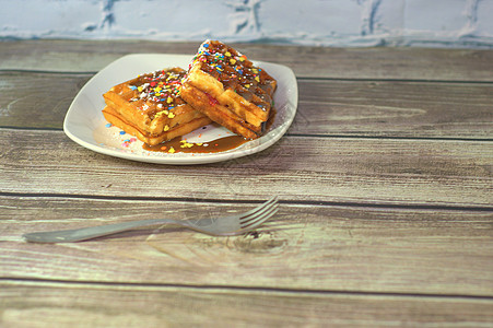 Viennese华夫饼和巧克力冰淇淋 躺在白色板块上 桌子上的叉子对着砖墙烹饪美食甜点用具胡扯食物早餐饼干蛋糕盘子图片
