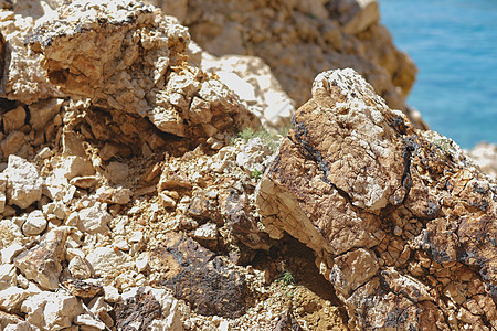 克罗地亚码头明亮而高对比度的岩石石灰岩垂直风化海岸橙子裂缝编队石纹花岗岩石板背景图片