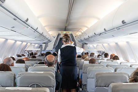 商业飞机内部 空姐在飞行期间坐在座位上服务乘客 b 客机内空气旅游工作运输娱乐男人屏幕经济航空公司航班图片