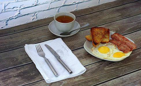 早餐 炸鸡蛋 培根和面包条的盘子 还有一杯茶 餐巾纸上的餐具在桌边靠着面包食物桌子美食油炸皮疹厨房饮食营养餐巾图片