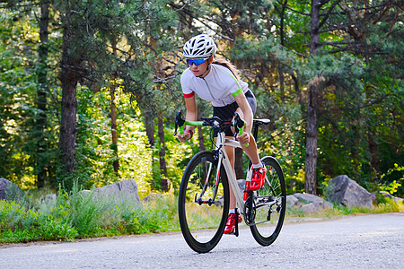 青年女赛车手骑着路自行车在夏日热火的森林中走免费道路 健康生活方式概念自由活动速度女性城市晴天成人公园森林爱好图片