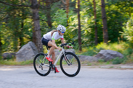 青年女赛车手骑着路自行车在夏日热火的森林中走免费道路 健康生活方式概念晴天运动女孩女性城市成人街道公园速度自由图片